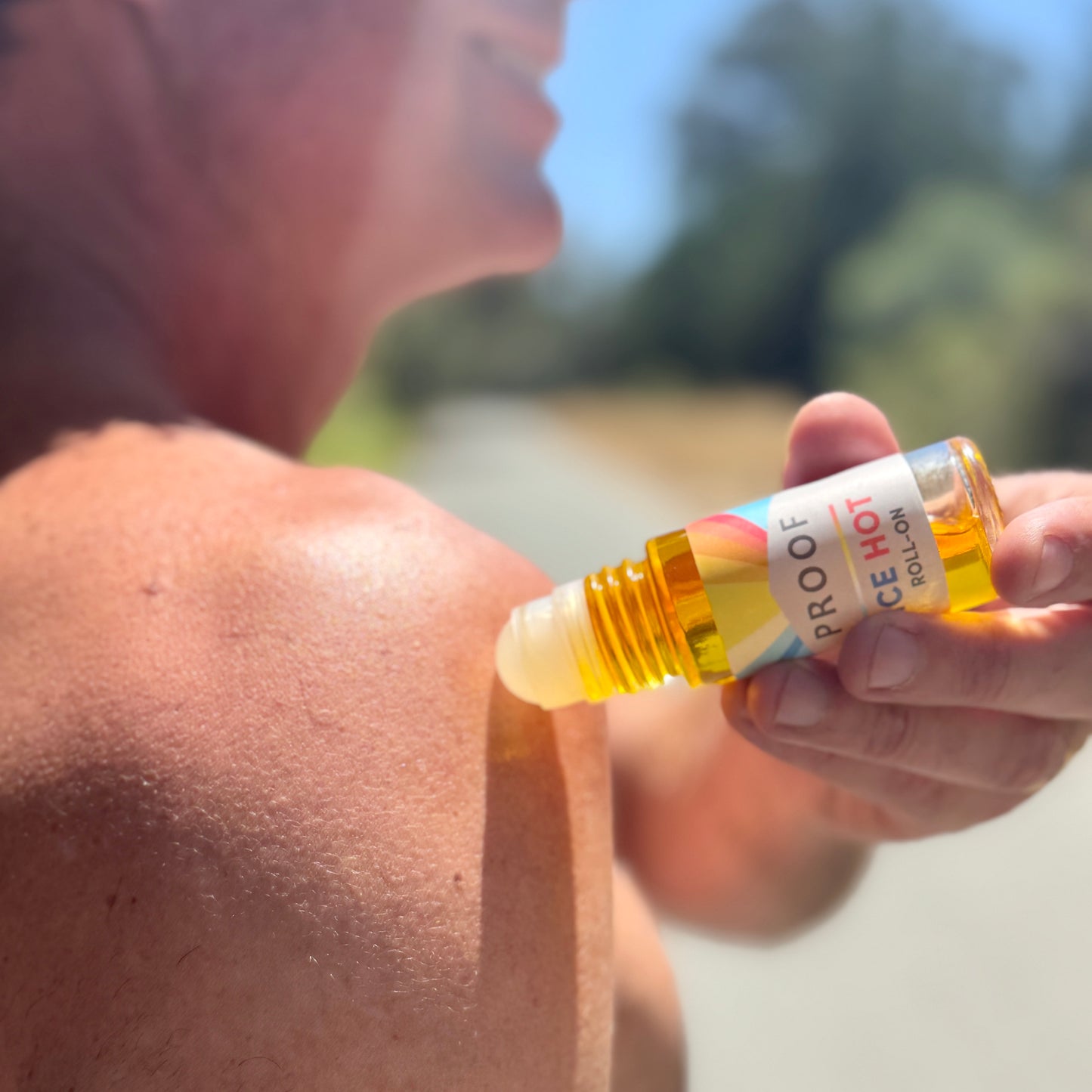 Man applying Proof Remedy Ice Hot Roll-On with CBD to shoulder outdoors for natural muscle and joint pain relief.