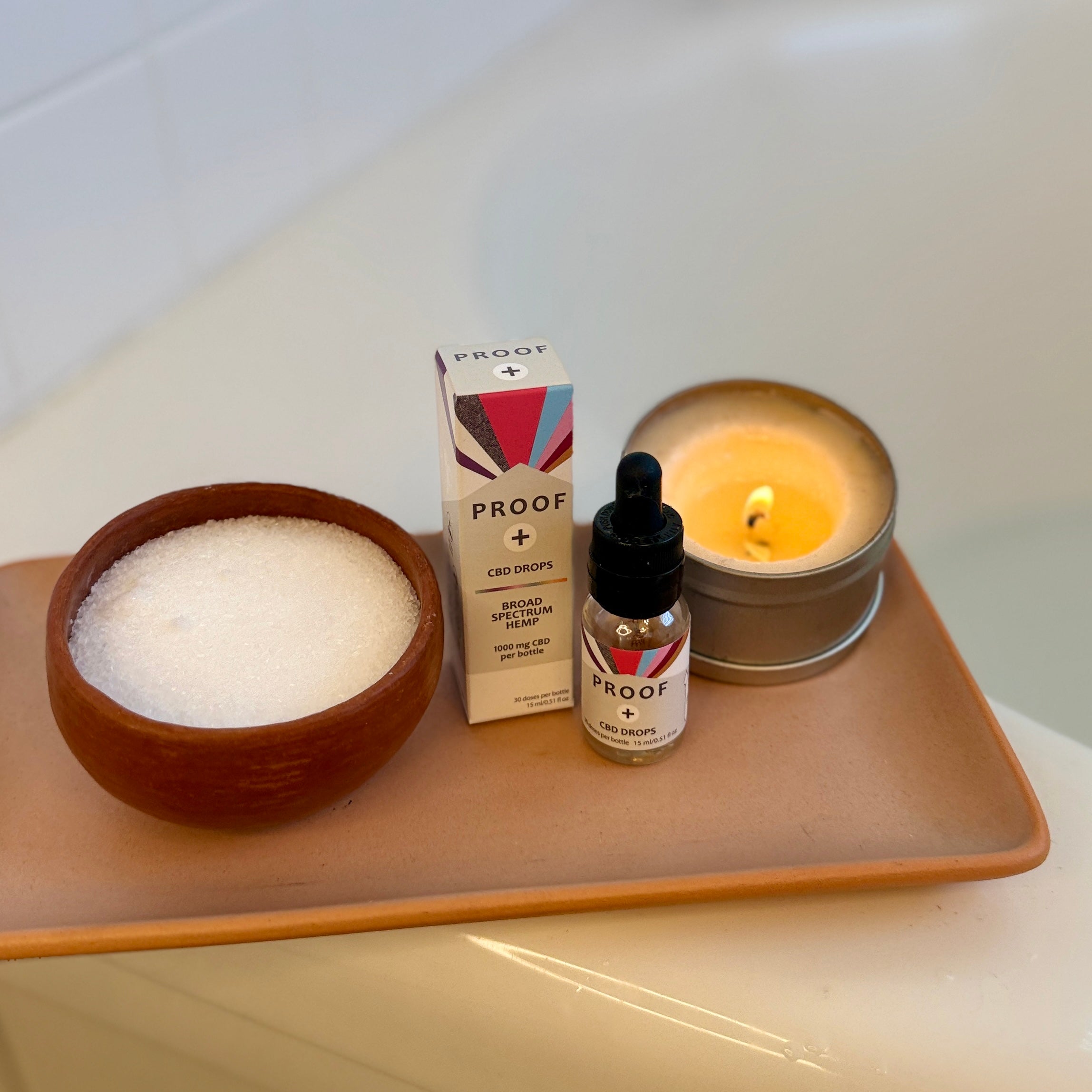 Proof CBD drops next to a bowl of bath salts