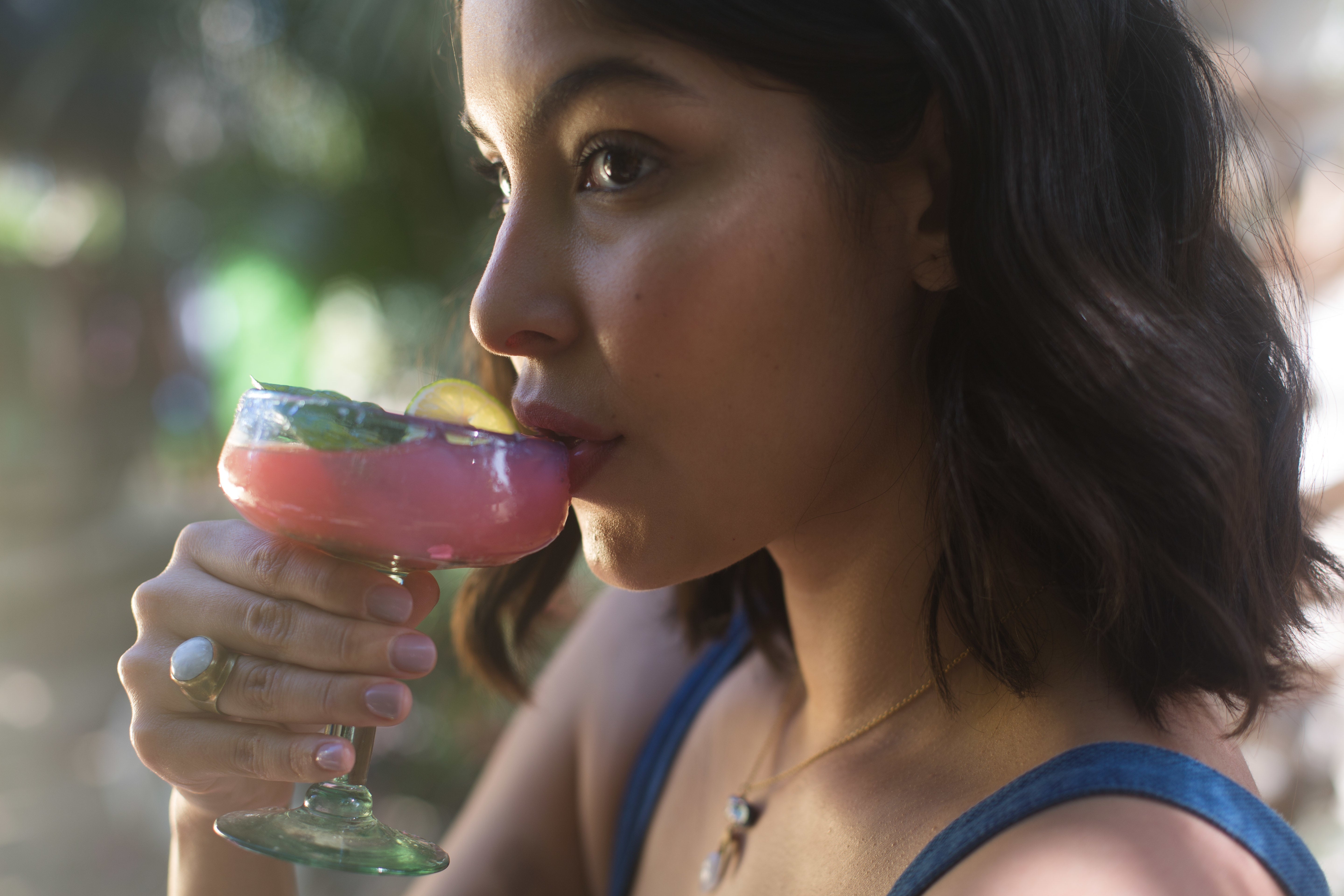 Woman enjoying a Proof CBD infused mocktail outdoors on a sunny day.