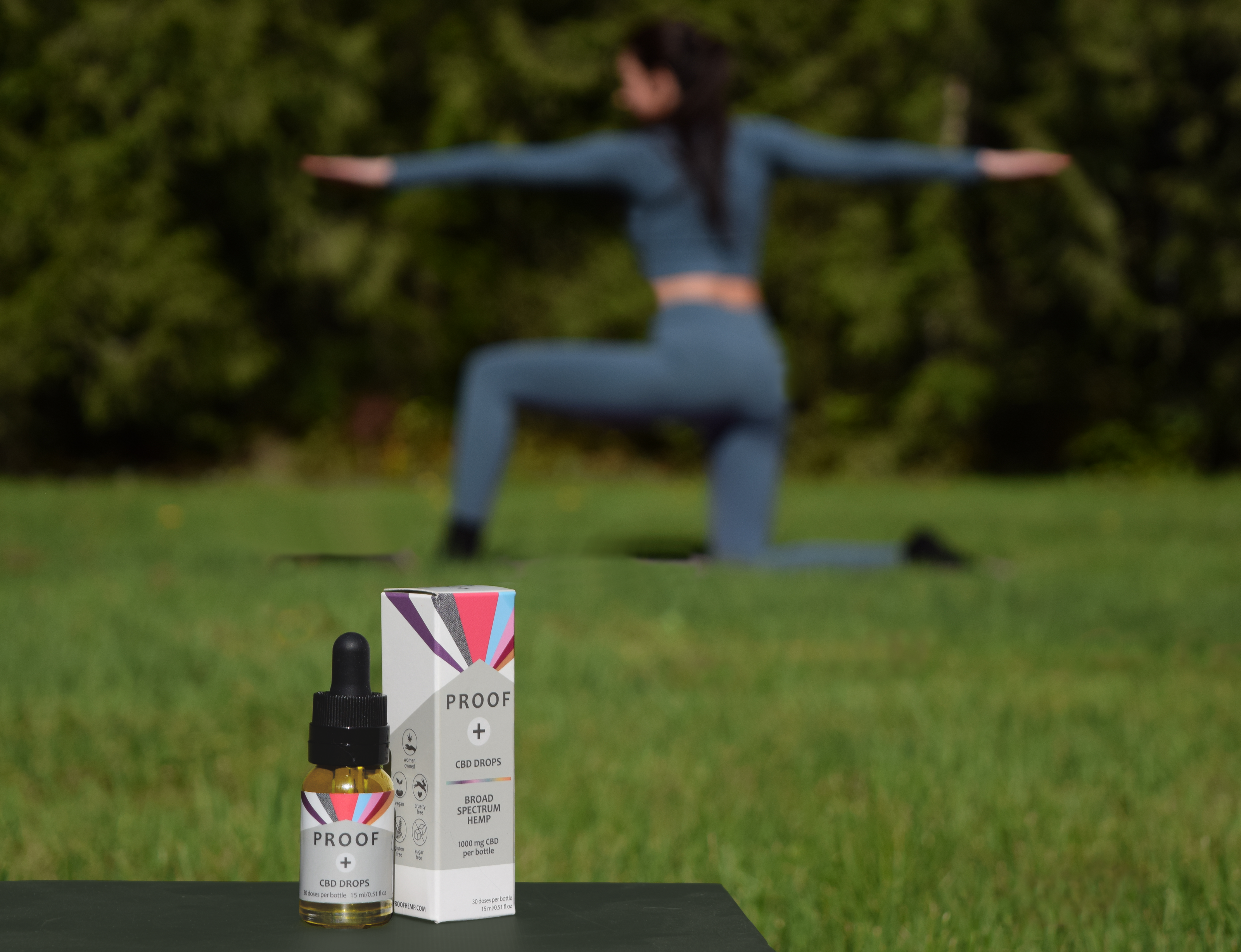 Proof CBD Drops with woman doing yoga in the background.